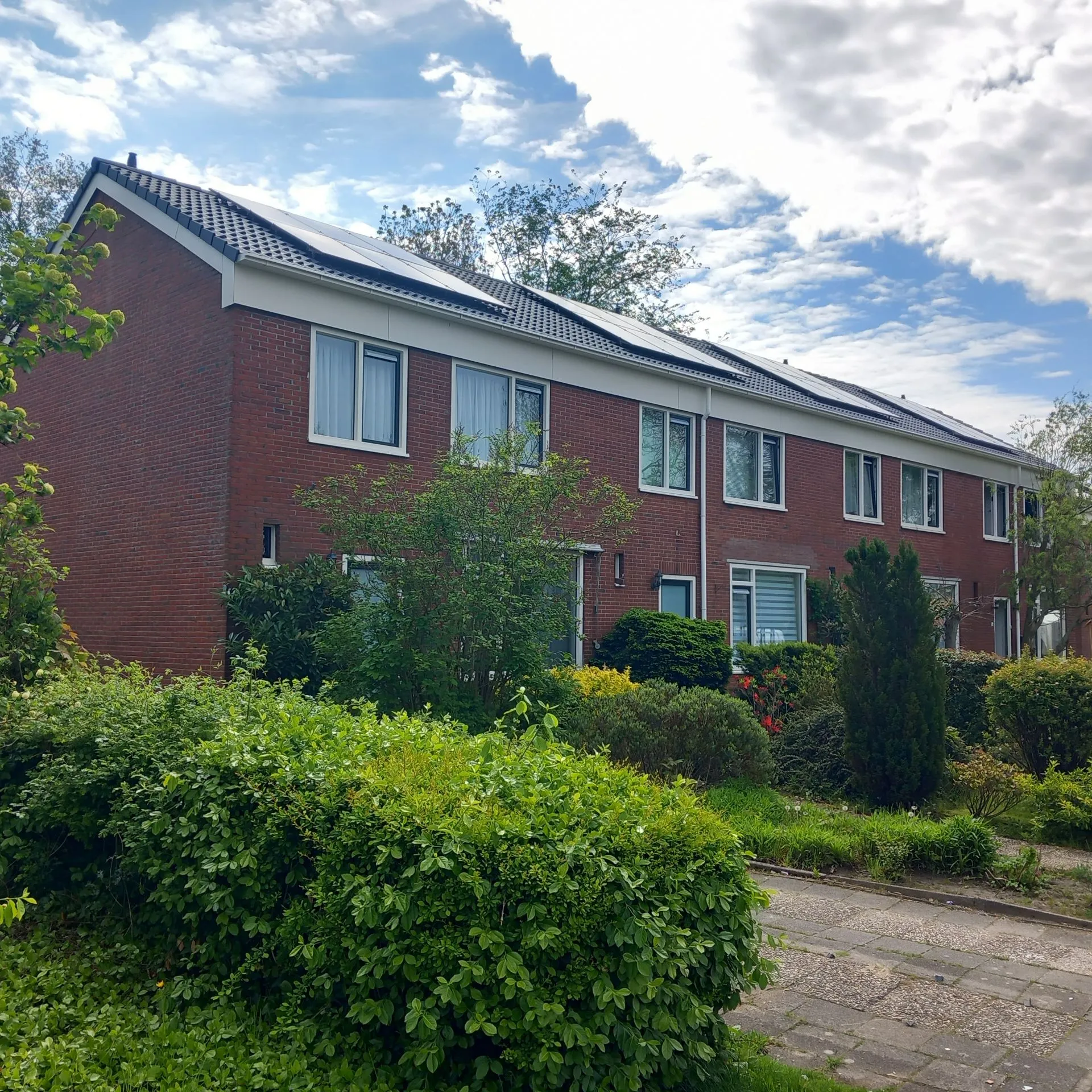 Zij-aanzicht van een rijtjeswoning in Zuidhorn met witte kunststof kozijnen en zonnepanelen