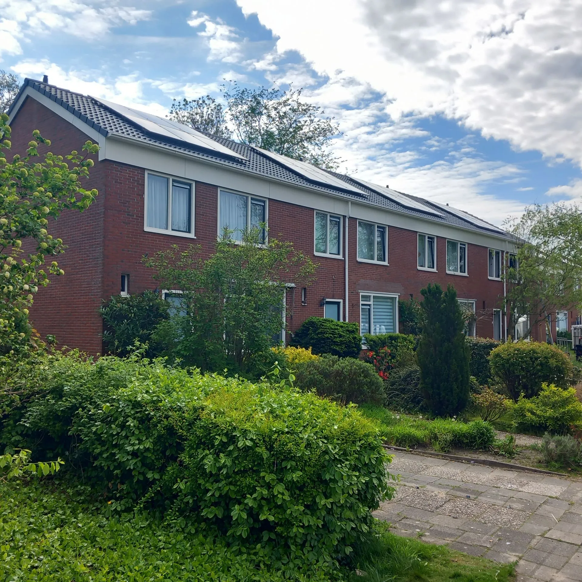 Zijkant van een rijtjeswoning in Zuidhorn met witte kunststof kozijnen en zonnepanelen