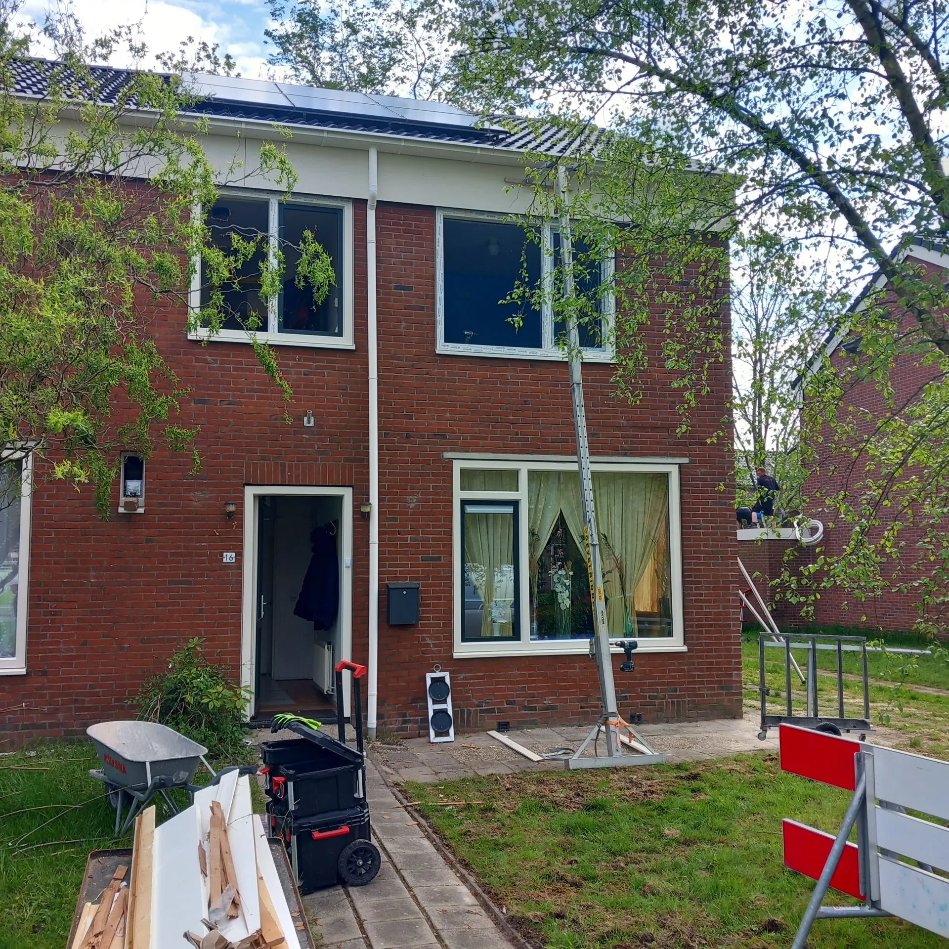 Een bakstenen hoekwoning in Zuidhorn met bouwmateriaal ervoor