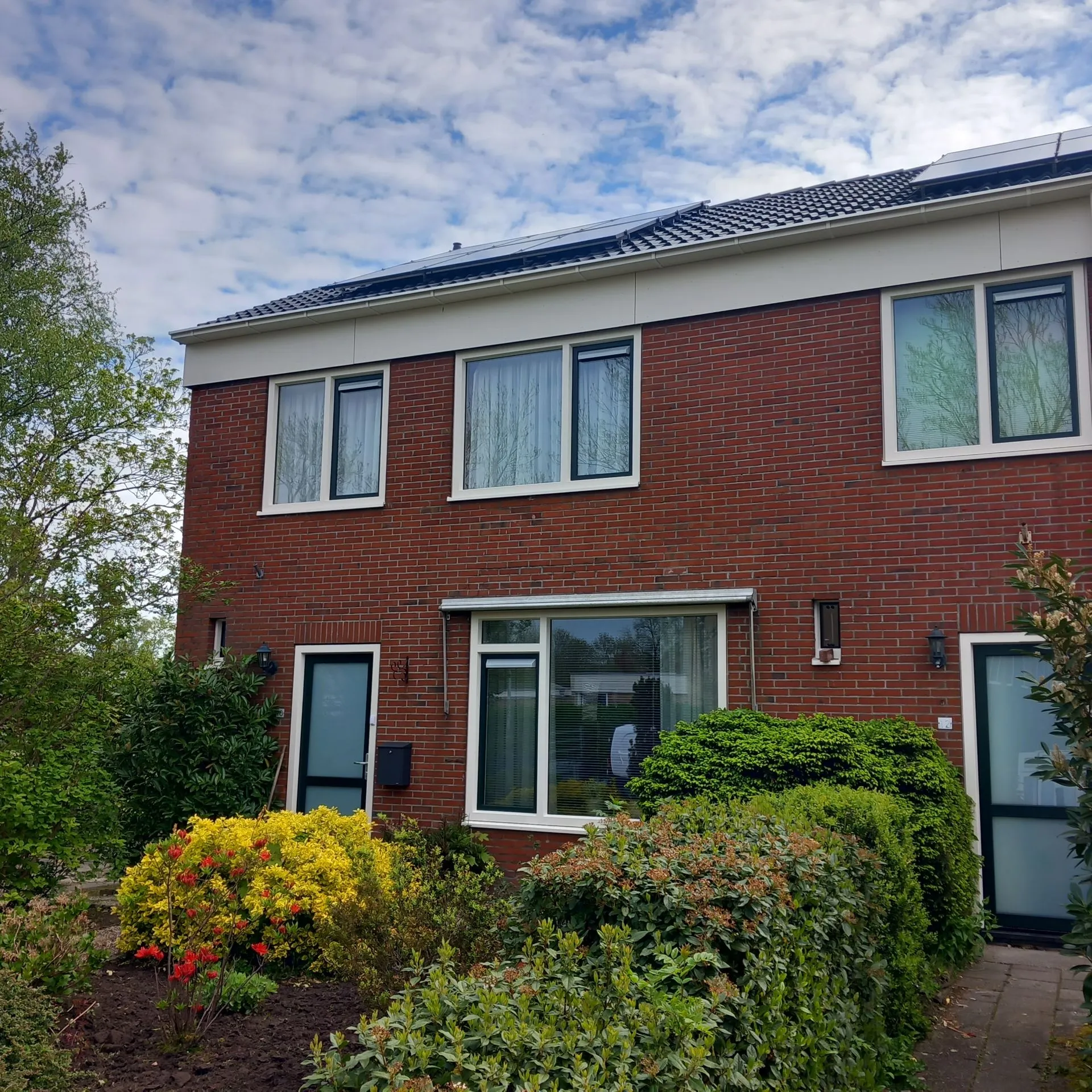 Een hoekwoning van voren met wit en zwarte kunststof kozijnen