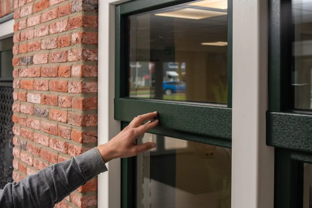 Hand die naar een donkergroen kozijn wijst