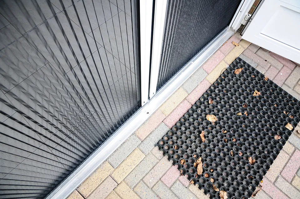 Plissehordeur detailfoto van bovenaf genomen met een deurmat