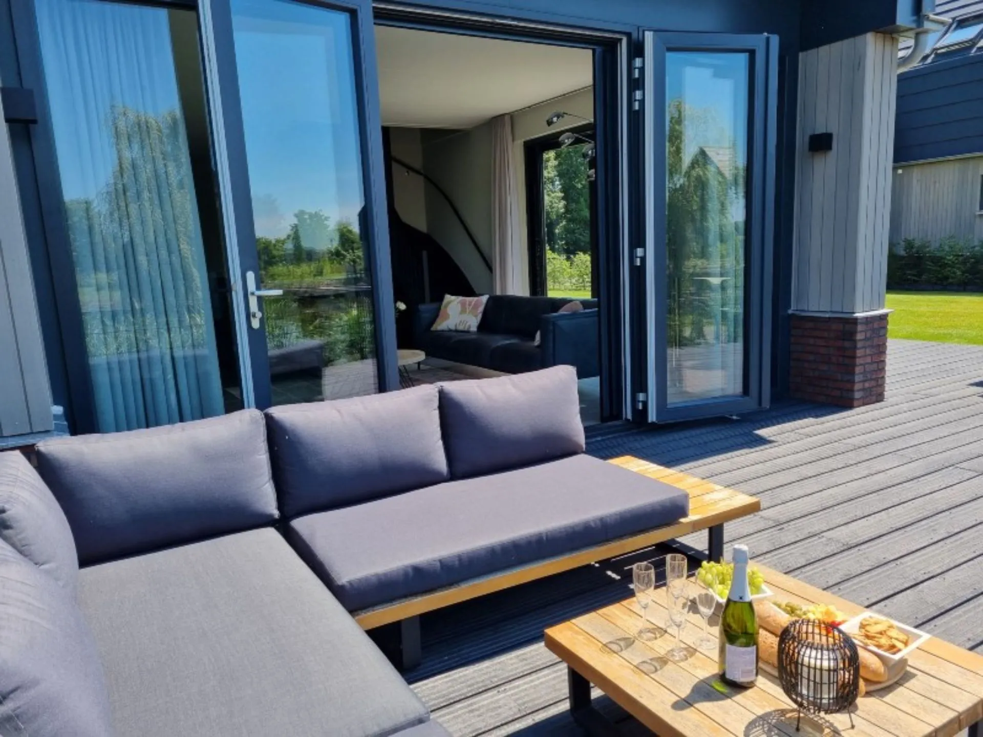 Woning vanaf buiten met tuinset ervoor en zwarte openslaande deuren