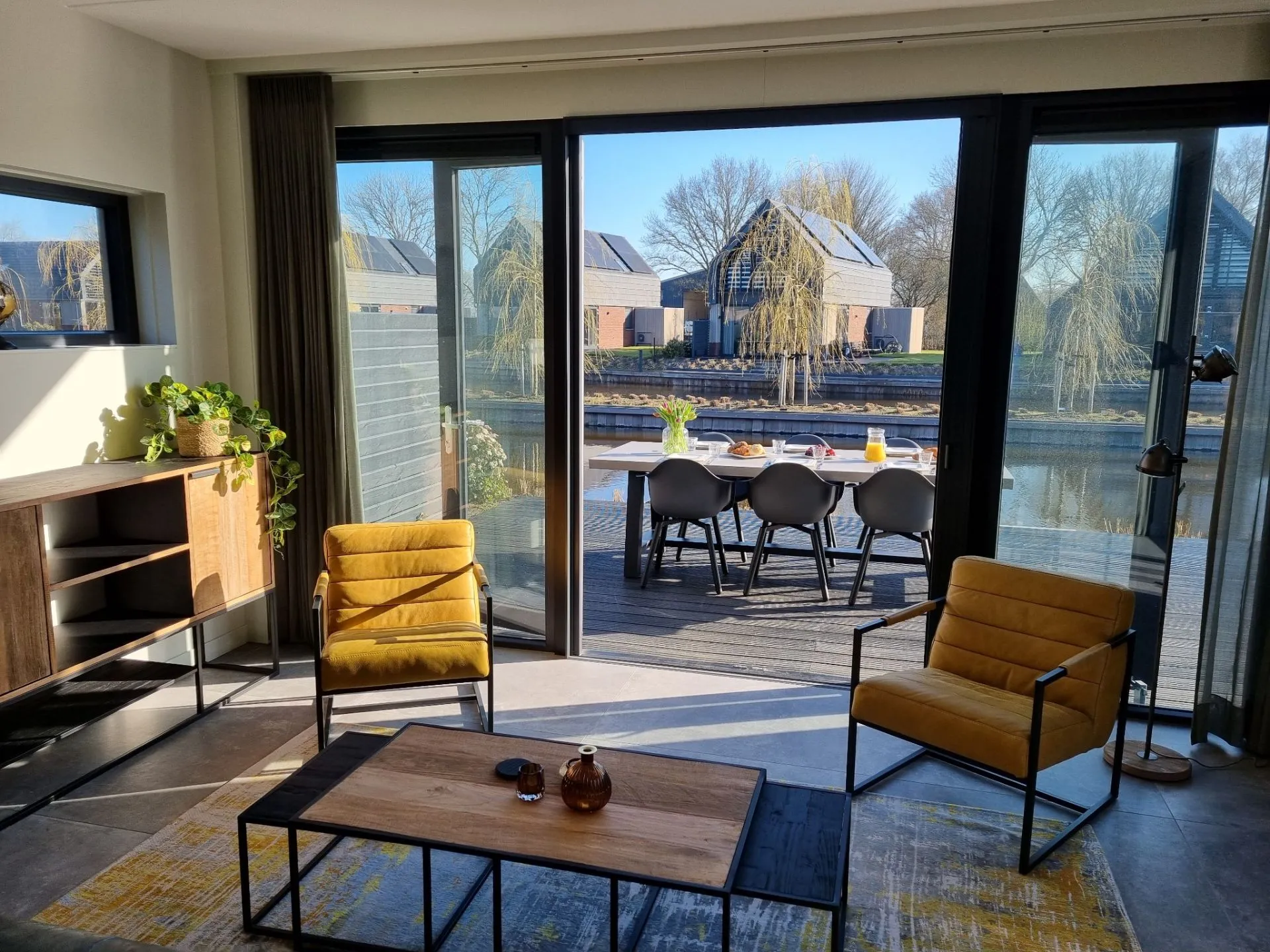 Woning van binnen met grote openslaande, zwarte deuren naar buiten aan het water