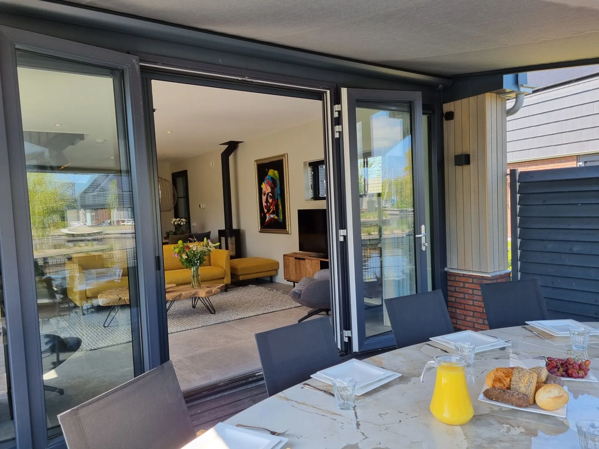 Een overkapping aan een woning vast met zwarte openslaande deuren