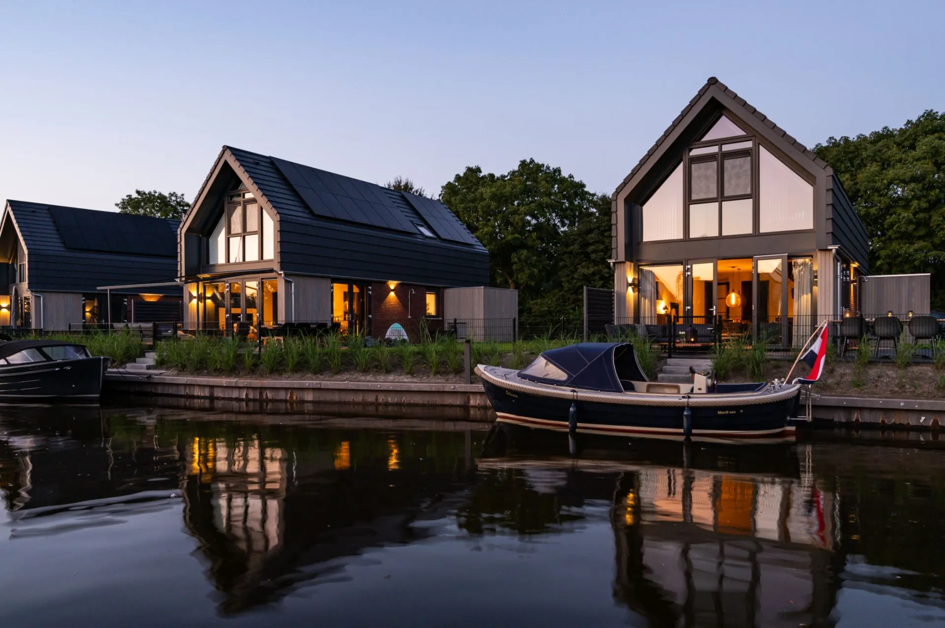 Vakantiehuisjes aan het water met grote zwarte ramen en kunststof zwarte kozijnen