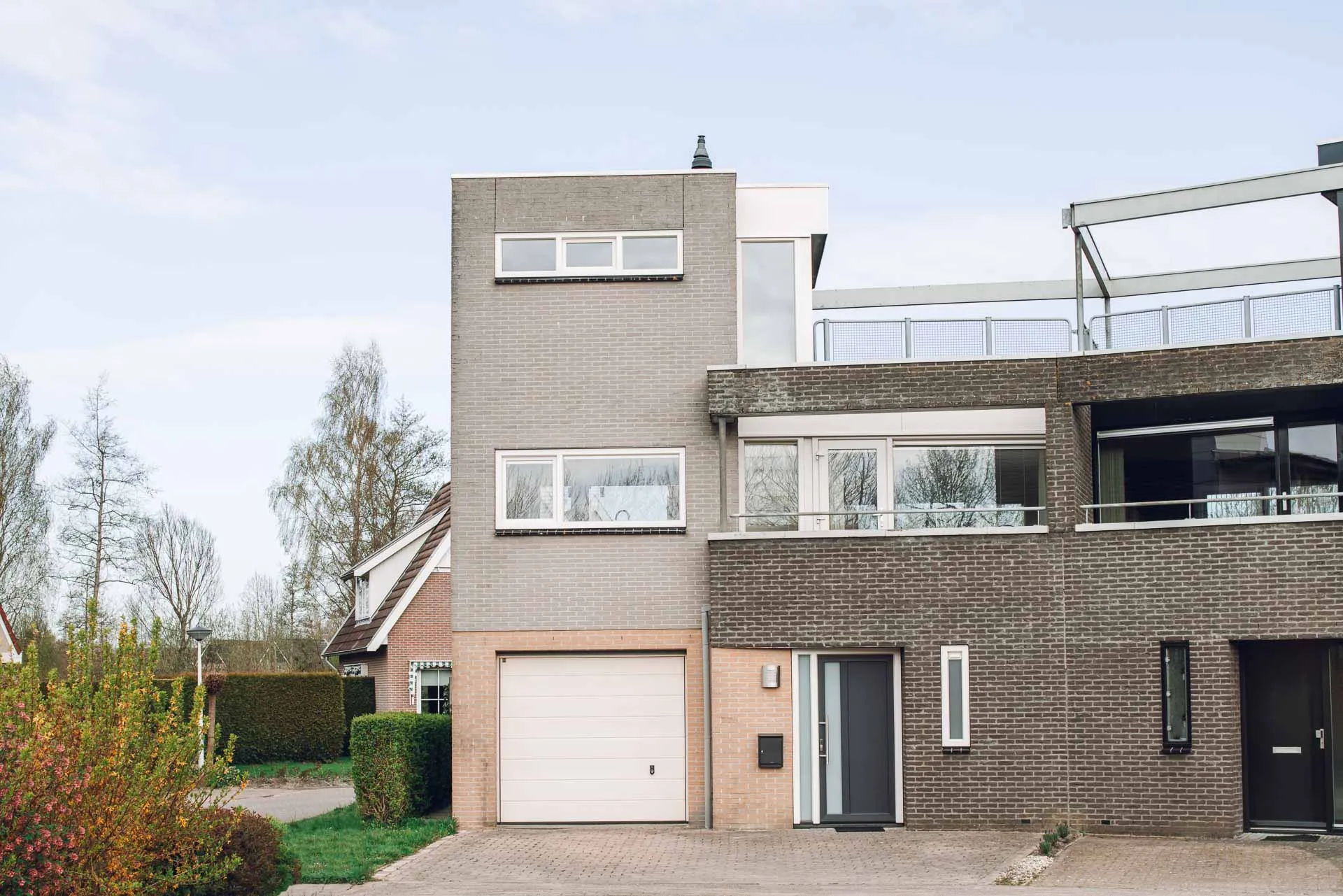 Voorkant licht en donker grijze woning met witte kozijnen en zwarte deur in Joure
