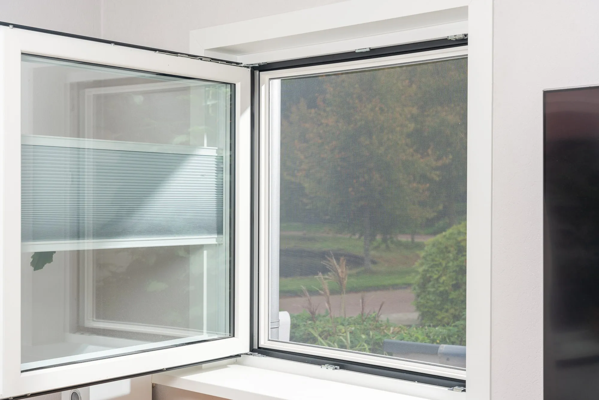 Geopend draaikiepraam met hor en plissegordijn.